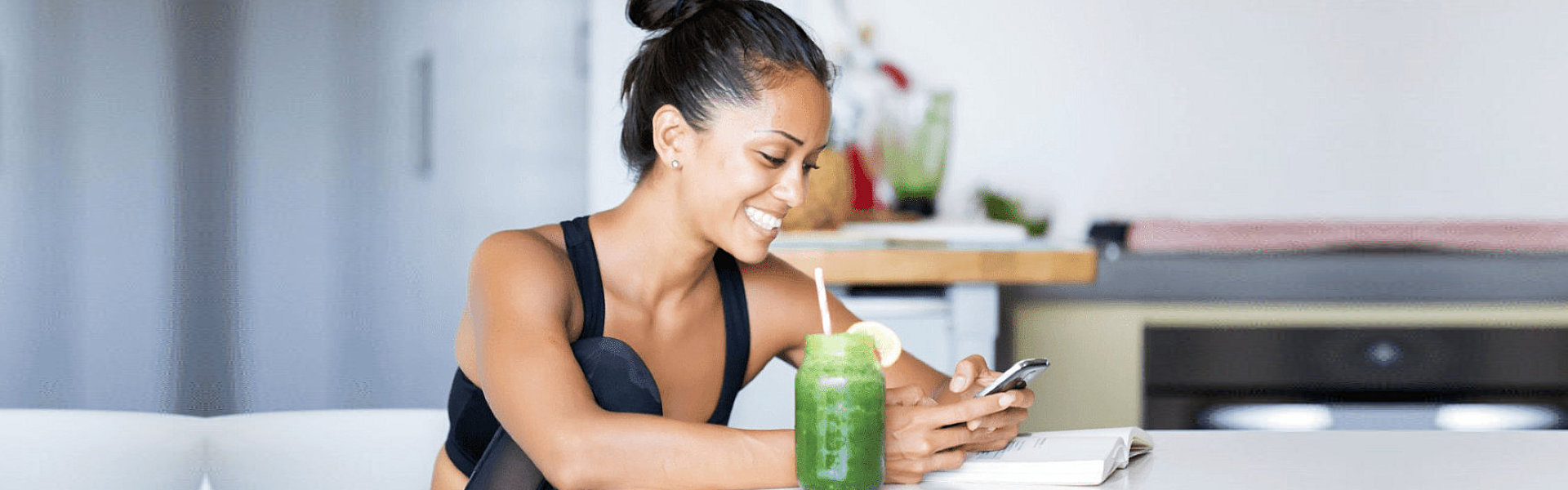 woman on desk texting while having a vegetable shake